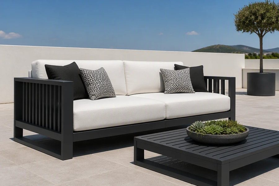An ivory white outdoor lounge sofa with a dark slatted coffee table holding a shallow planter