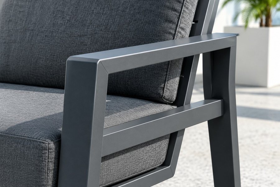 A close view of a grey woven outdoor cushion resting on a charcoal aluminium sofa frame