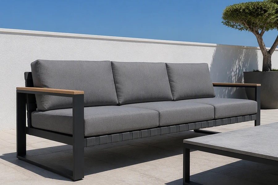A mid grey three-seat outdoor sofa with a charcoal frame and wood-look armrest caps, beside a coffee table