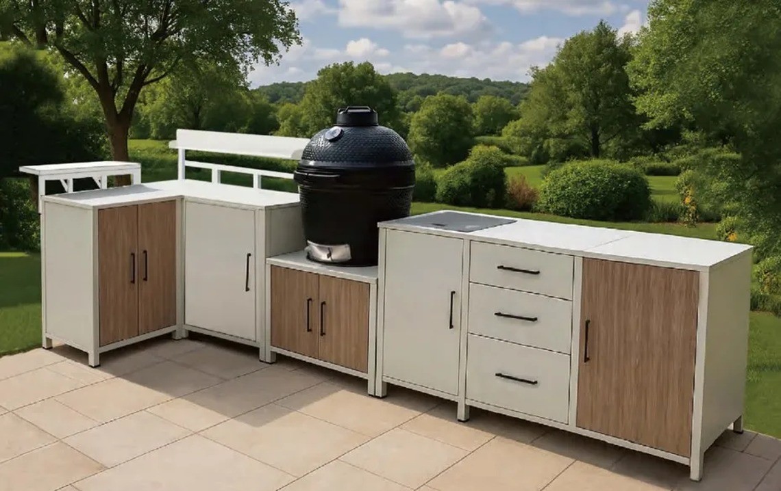 A white and tan outdoor kitchen installed in a garden on a paved patio with a kamado grill
