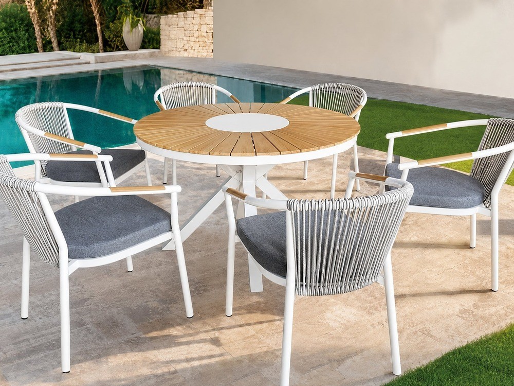 White rope-weave outdoor dining chairs around a round timber slat table beside a pool