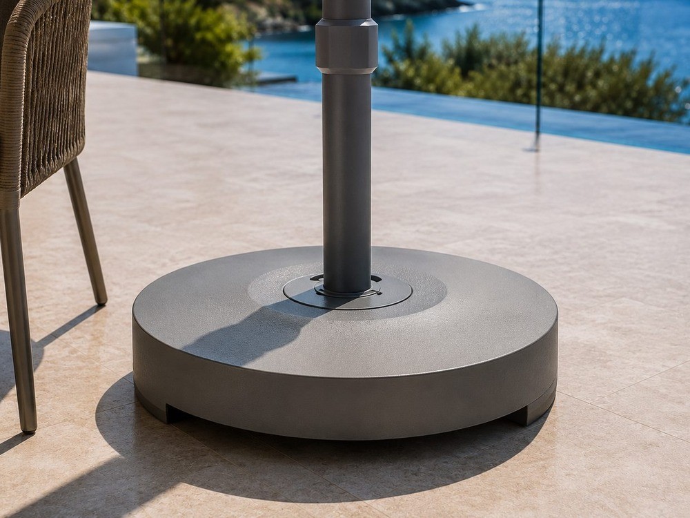 Concrete umbrella base with a centre pole socket on a stone terrace above an infinity pool