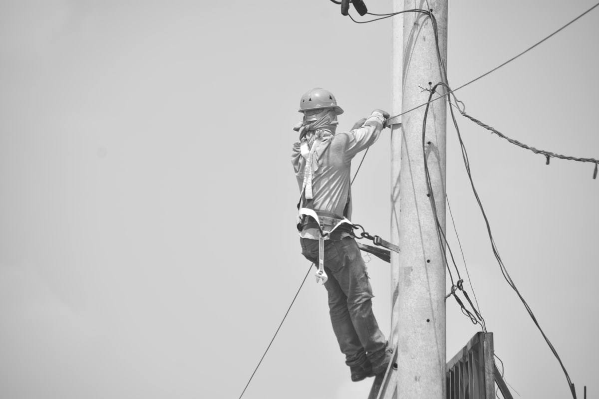 Utility lineman using a safety harness at height