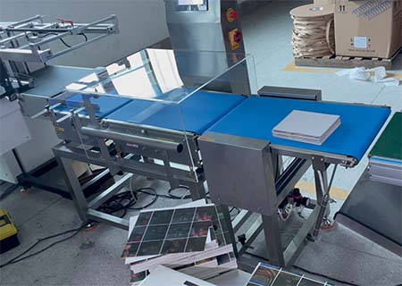 Dynamic checkweigher integrated into printed card production and packaging line