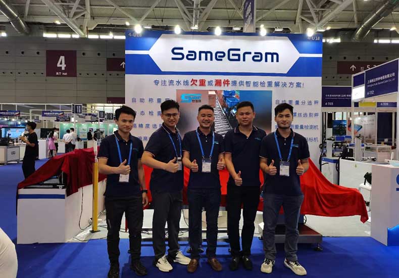 SameGram team at trade show booth showcasing industrial checkweigher machines and inspection systems