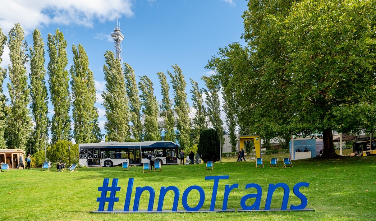 The #InnoTrans lettering on the Summer Garden lawn at the Berlin Exhibition Grounds, with a display bus and the Berlin radio tower in the background