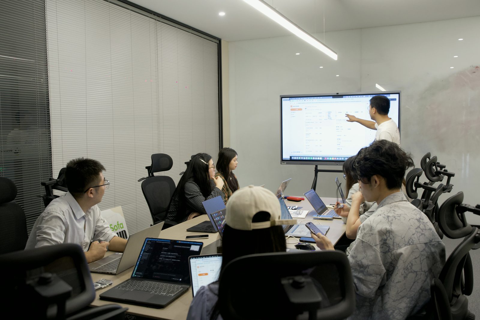 A colleague presenting the customer research workflow on the meeting room screen.