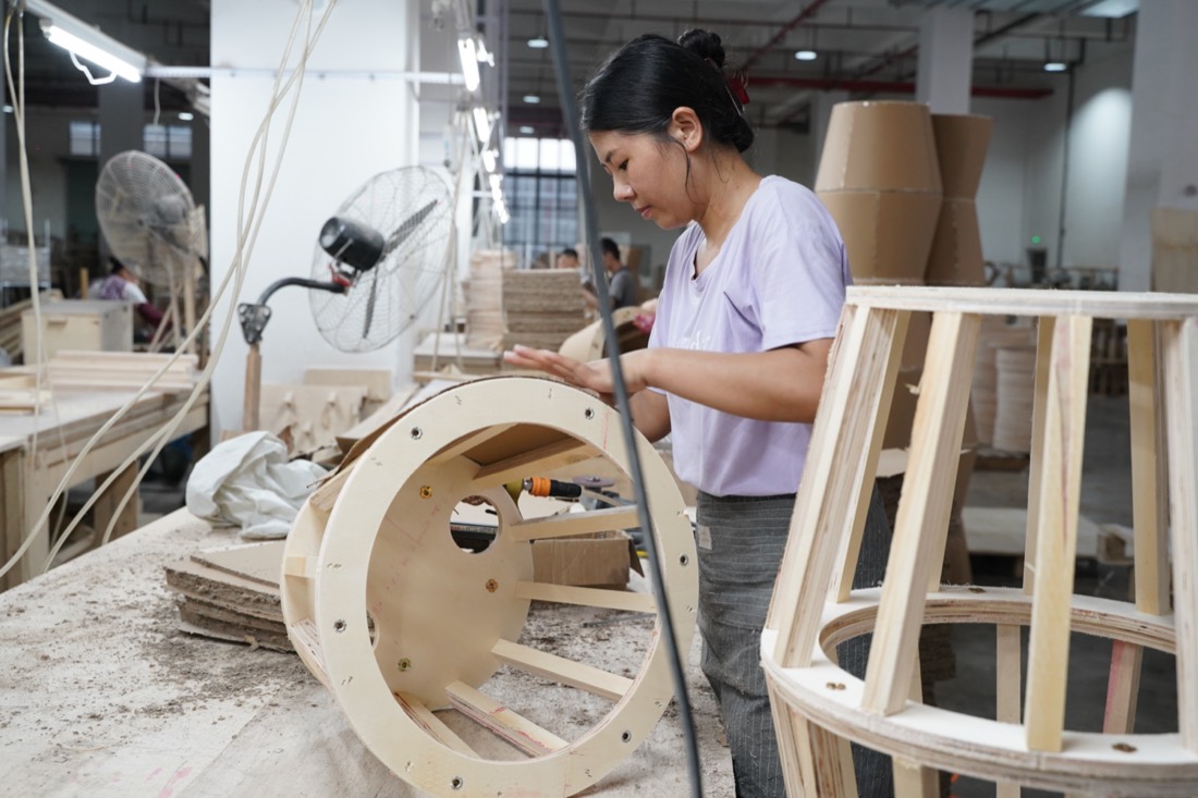 Worker assembling a wooden swivel base frame for a recliner chair in the workshop
