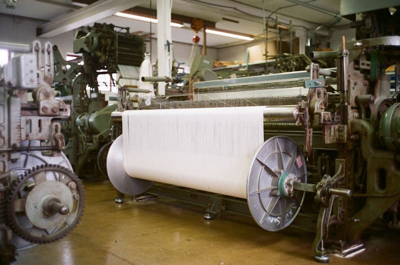 Industrial textile looms with large spools of thread in a modern manufacturing facility