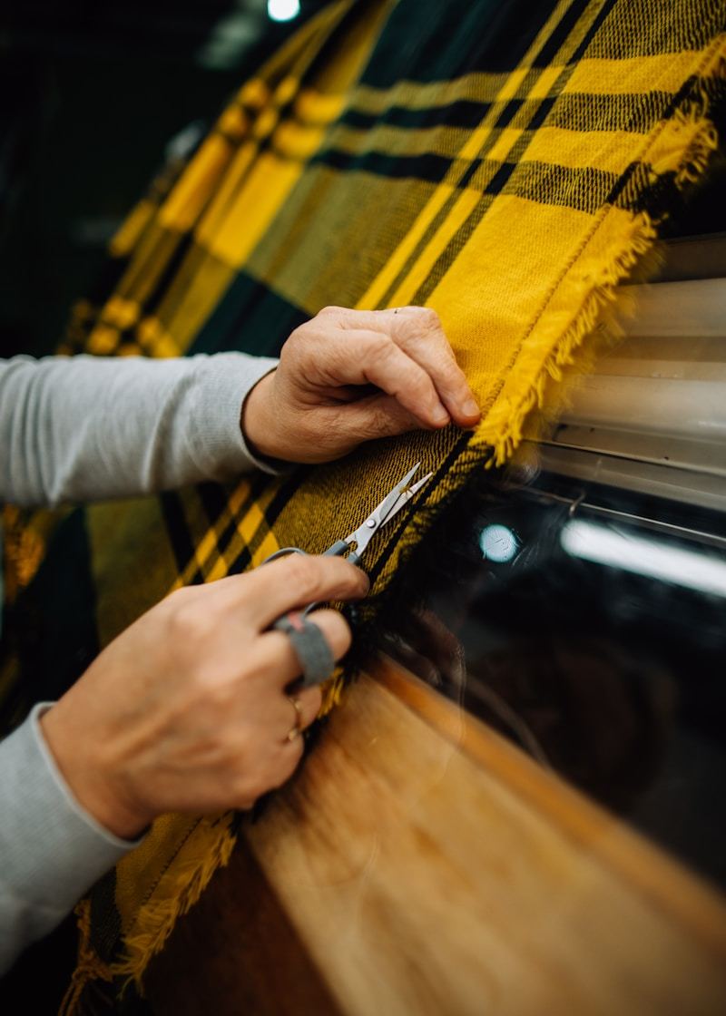 A person cutting fabric with scissors in a textile production workshop