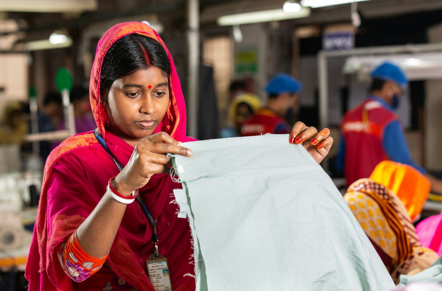Factory worker inspecting light blue fabric in a textile mill