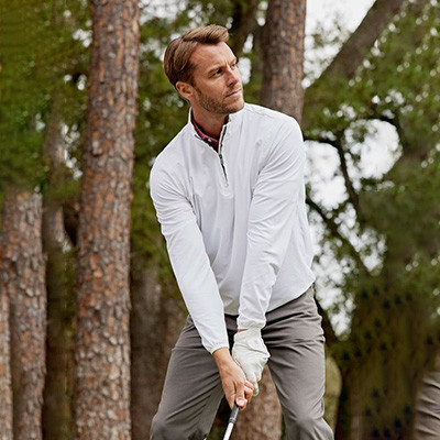 Golfer in performance jacket mid-swing on fairway