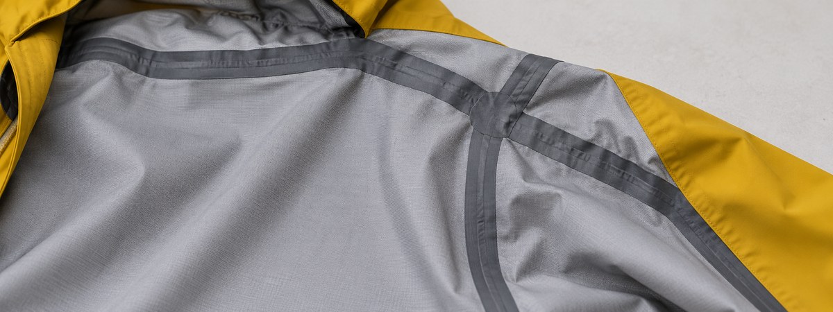Gray inner hardshell backer with seam sealing tape covering a seam junction