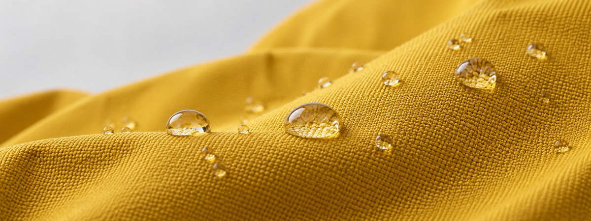 Water droplets on mustard-yellow woven shell face fabric