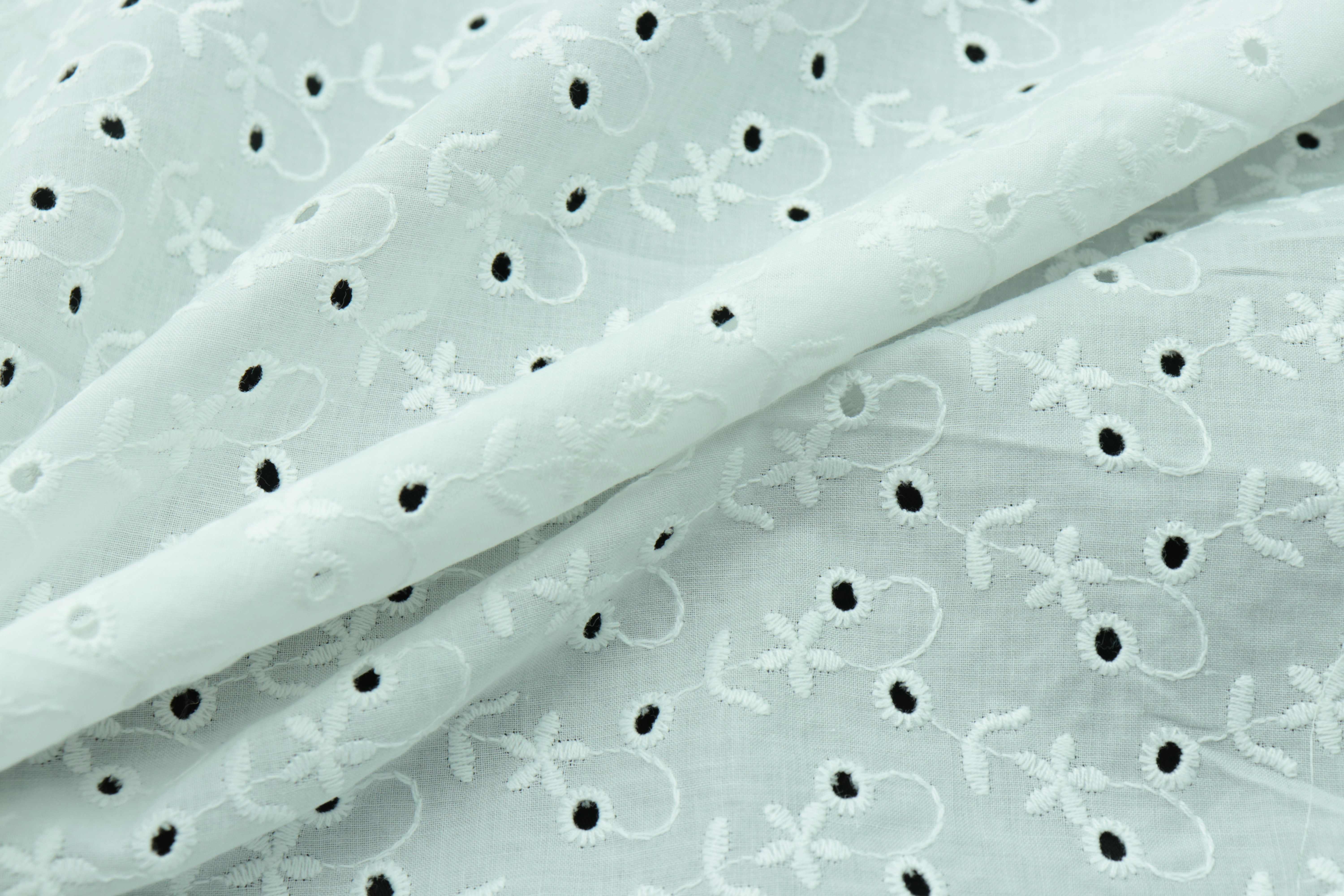 A side-by-side comparison of nylon and polyester fabric rolls, highlighting their different textures.