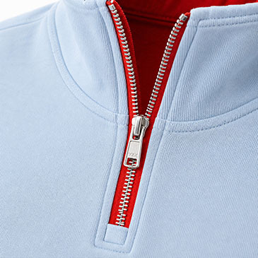 Detalle del cuello alto, borde rojo con forma de onda y cremallera metálica de media longitud