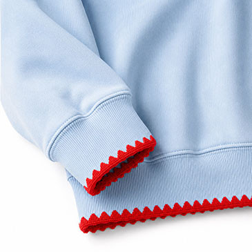 Detalle de los puños y el dobladillo en tono azul claro con borde rojo con forma de onda