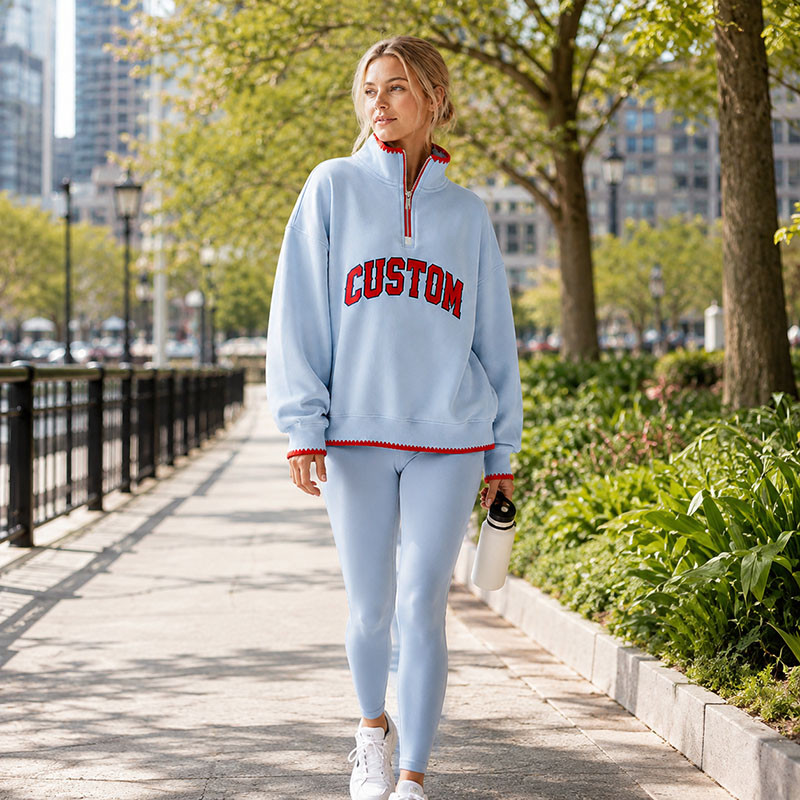 Mujer caminando por un parque urbano con una camiseta deportiva de media cremallera en tono azul claro