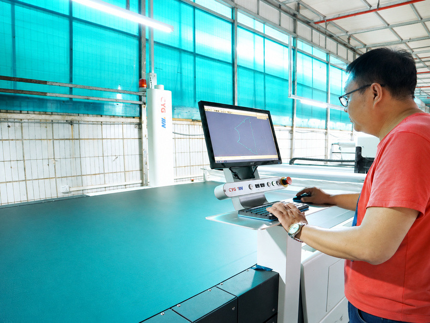 Technician adjusting a computer-controlled fabric cutting machine