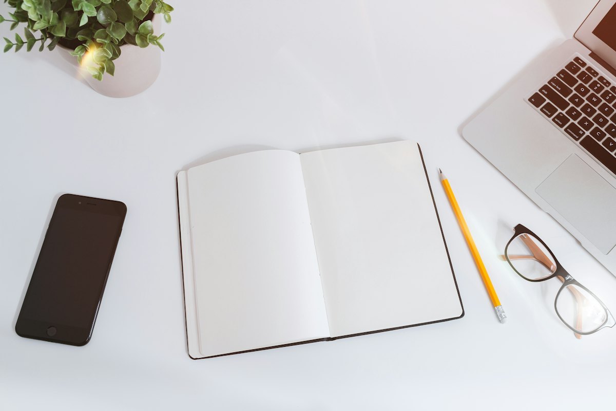Open notebook, pencil and laptop on a desk for organizing development notes