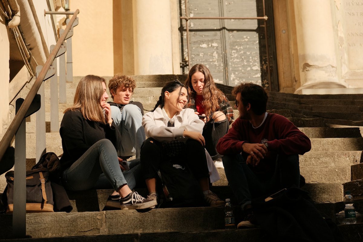 Group of young shoppers laughing together outdoors in warm light