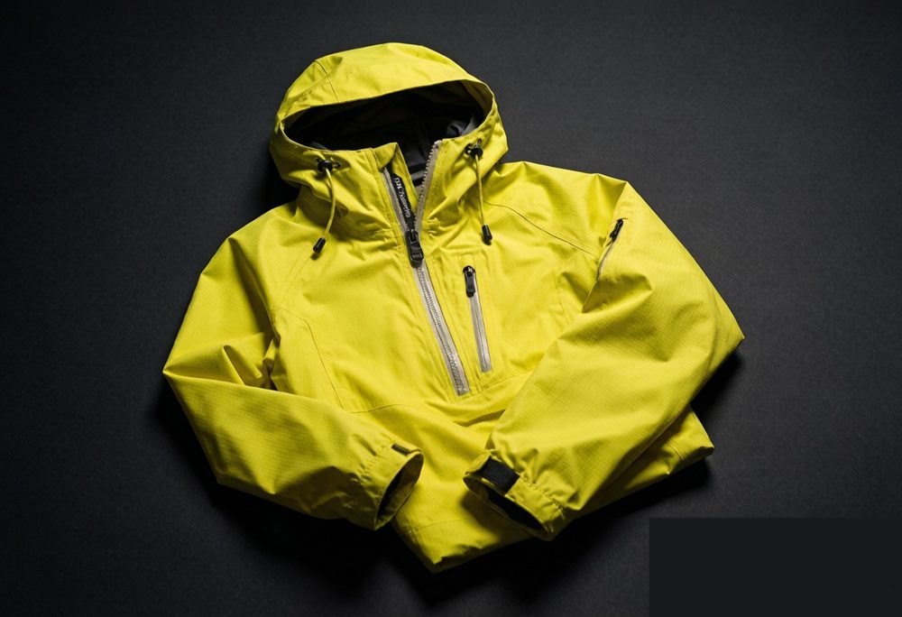 Technical yellow rain jacket with waterproof ripstop shell, taped seams, and adjustable hood - flat lay