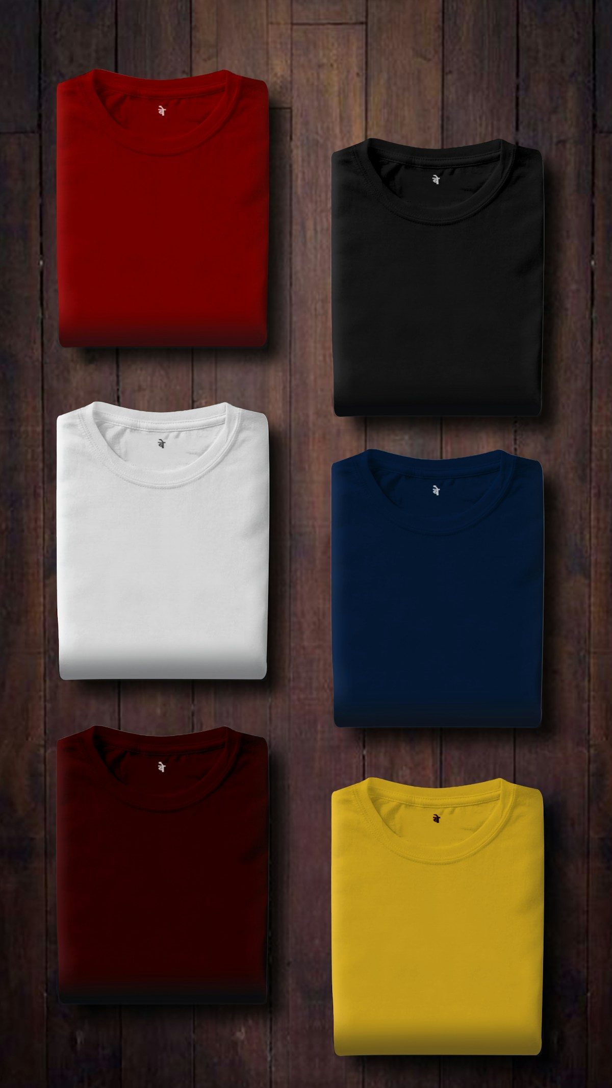 Colorful folded t-shirts in red, white, blue, burgundy, yellow on dark wood