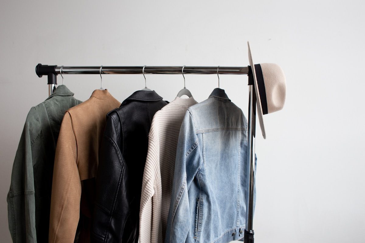 Jackets on a clothing rack with hats in various colors