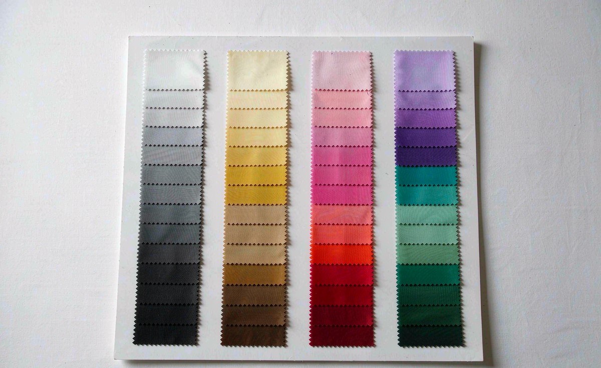 Factory woven nylon shell fabric colour card with four columns of pinked swatch strips grading from white to charcoal, cream to chocolate, pink to burgundy and lilac to forest green
