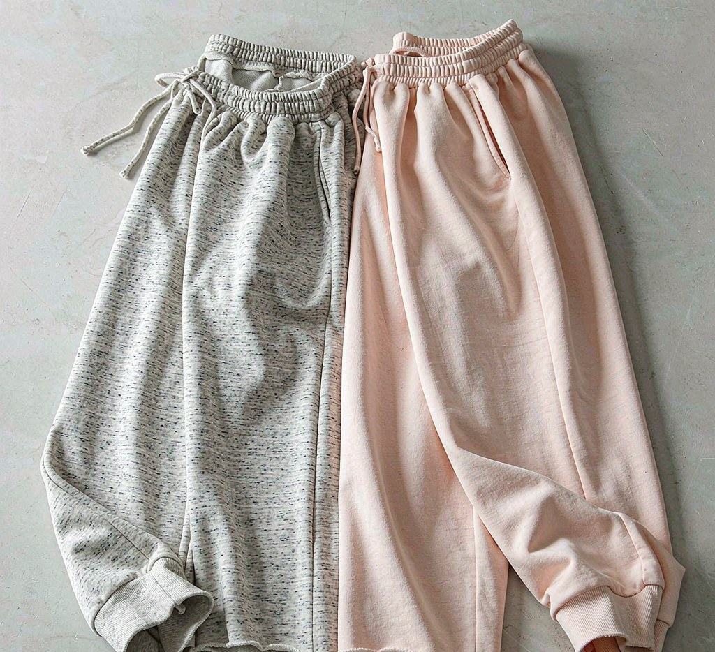 Grey and blush pink sweatpants with drawcord waistbands, side pockets and ribbed cuffs