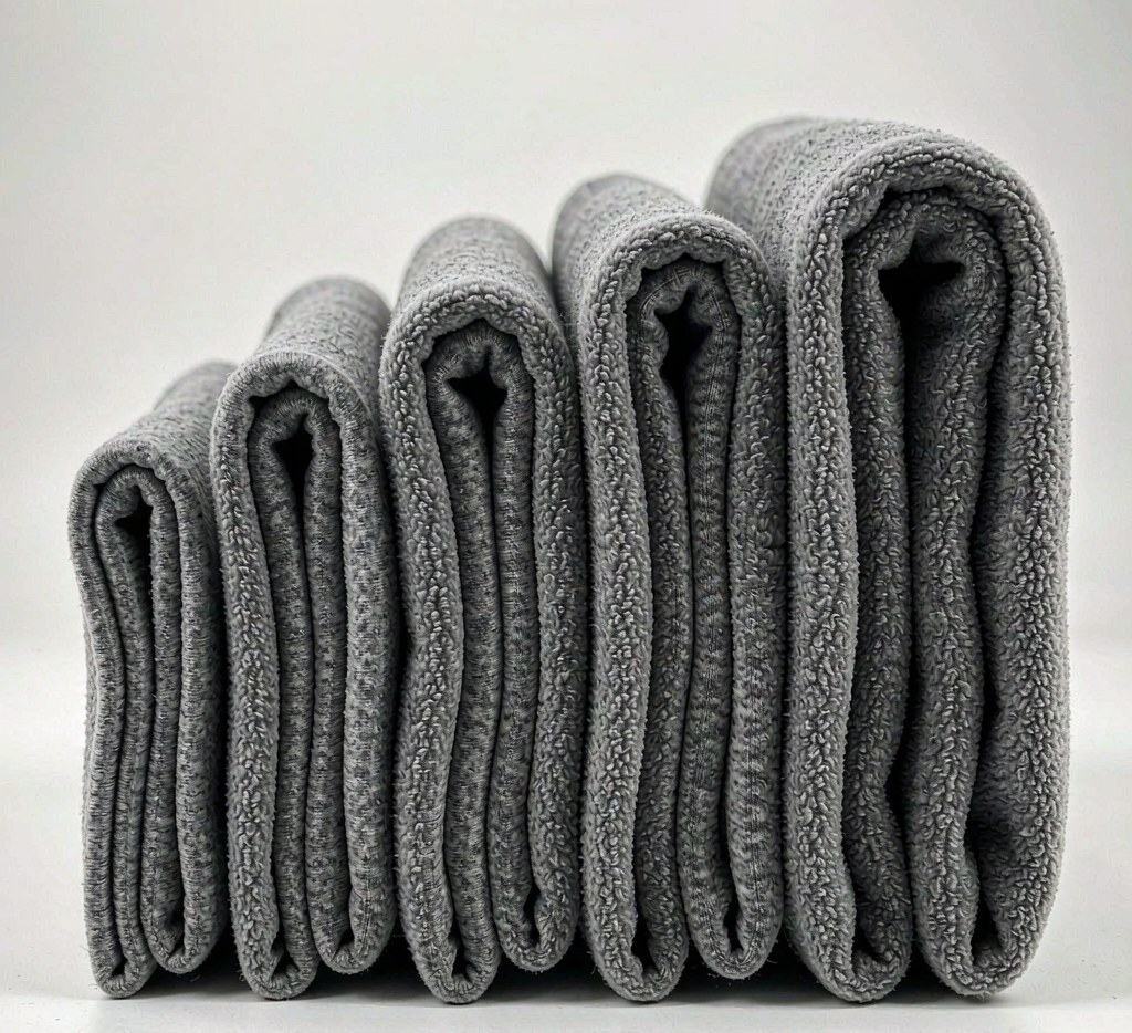 Five folded grey knit swatches shown side by side with different apparent thicknesses