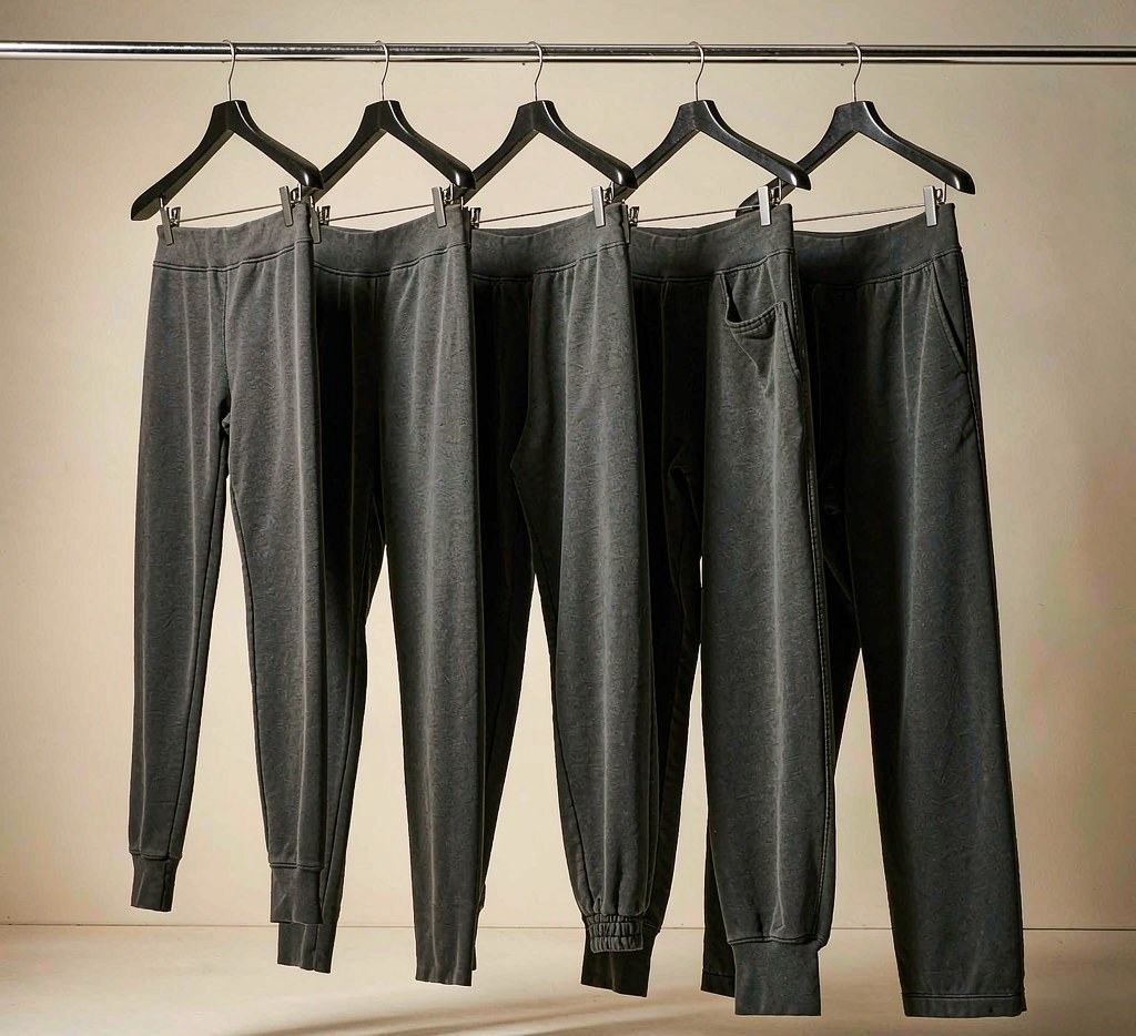 Grey sweatpants on a rail showing variations in leg width, cuffs and open hems