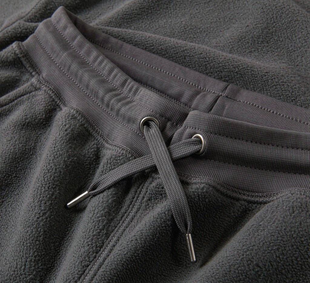 Close-up of a sweatpants waistband with a flat drawcord, reinforced eyelets and metal cord ends