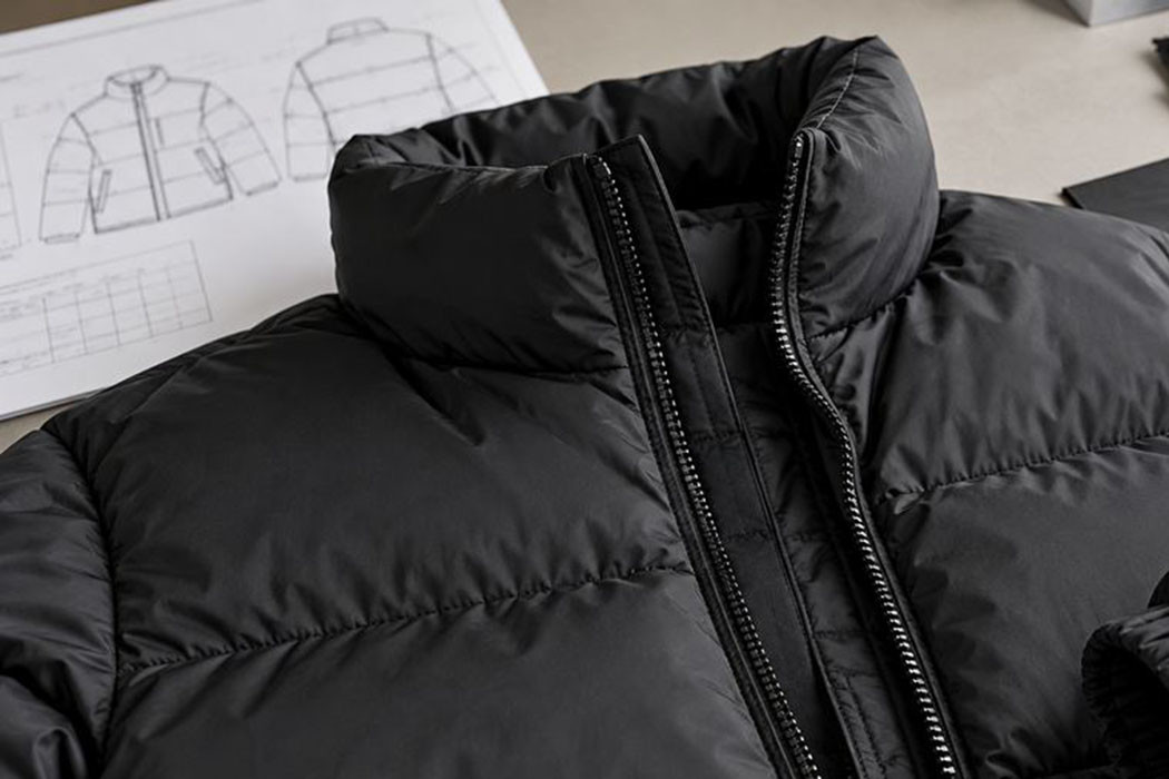 Illustrative fabric selection tabletop with black puffer shell swatches, white filling, zippers, trims and jacket tech pack sketches