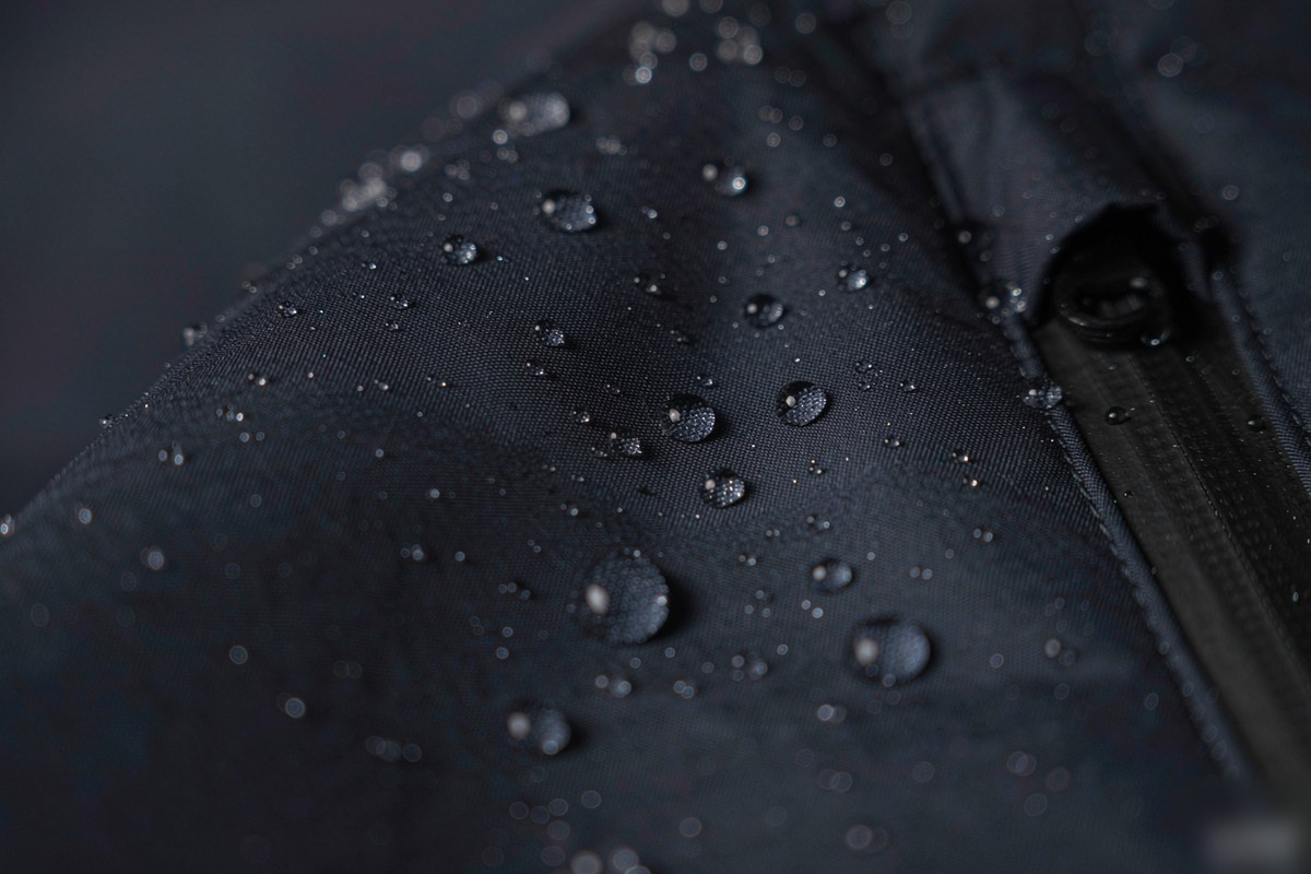 Illustrative water droplets beading on navy nylon fabric to explain water-repellent windbreaker finishes
