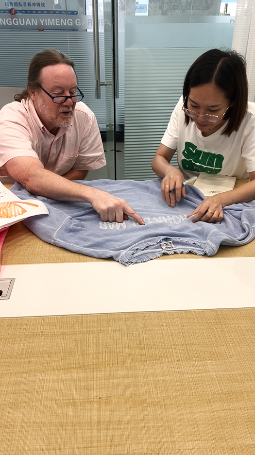 Carolin and visiting brand partner confirming print placement and design details on a washed sweatshirt sample