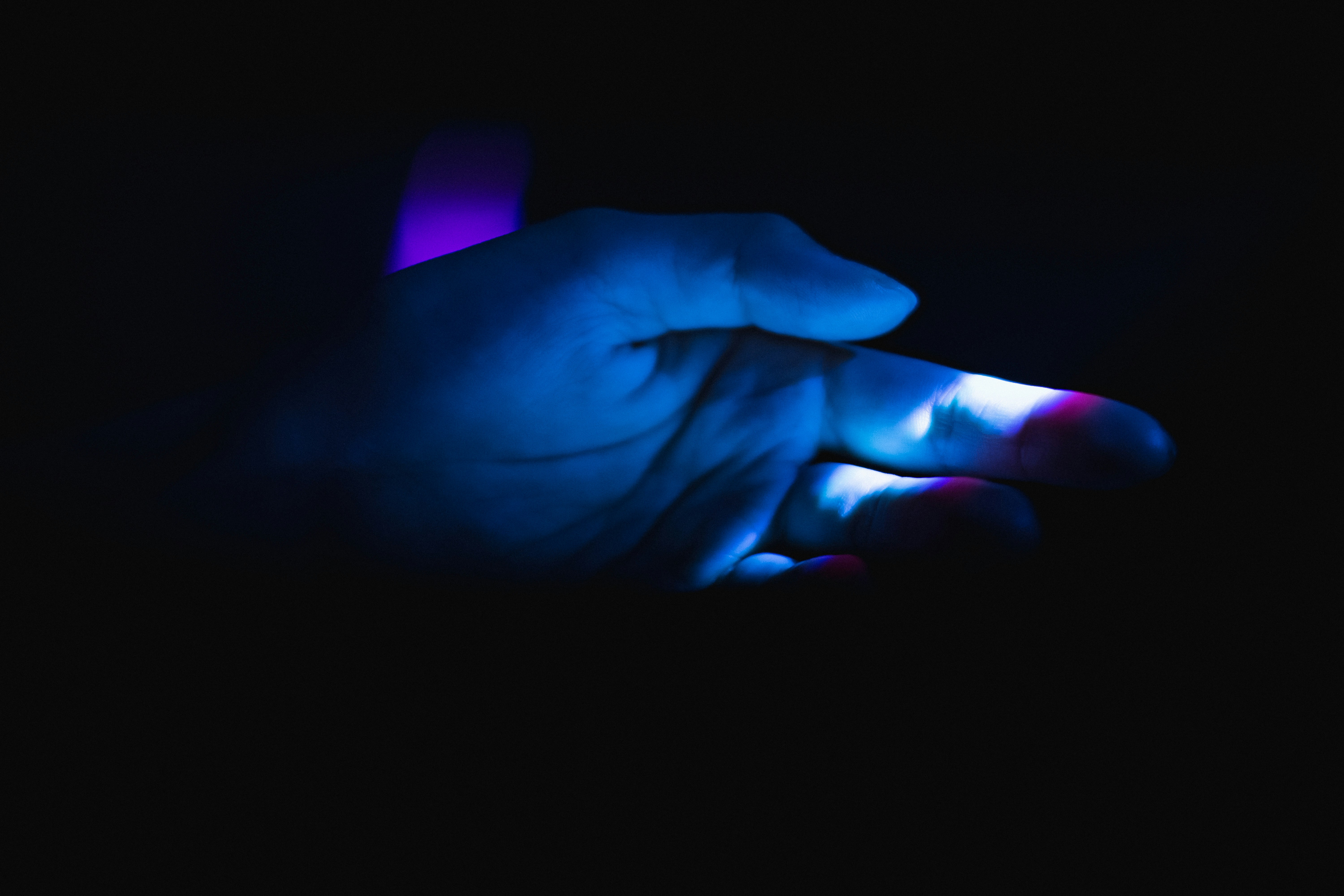 A hand holding a UV inspection light over a surface, revealing fluorescent details