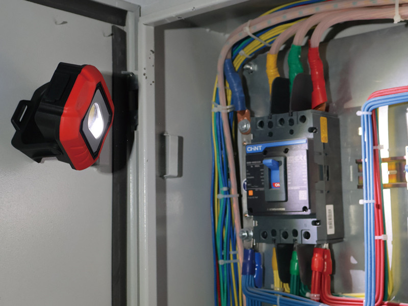 magnetic portable flood light mounted inside an electrical cabinet for hands-free maintenance lighting