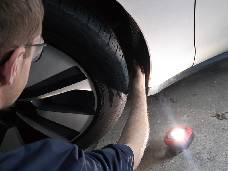 portable led flood light illuminating a vehicle wheel well during close-range automotive inspection