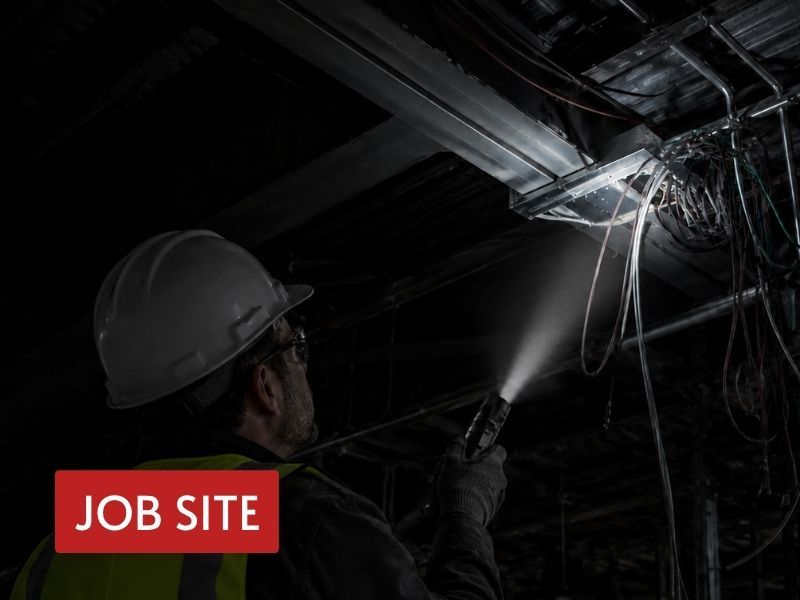 handheld light for edc used by a worker to inspect overhead wiring in a dark jobsite space