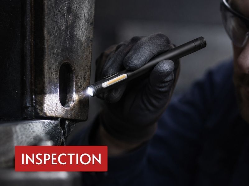 pen uv light used by a gloved technician to inspect a narrow opening in metal equipment