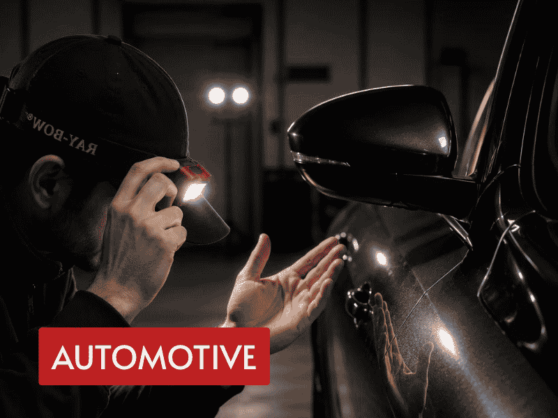 automotive led headlamp used for car body inspection beside a vehicle in a dark workshop