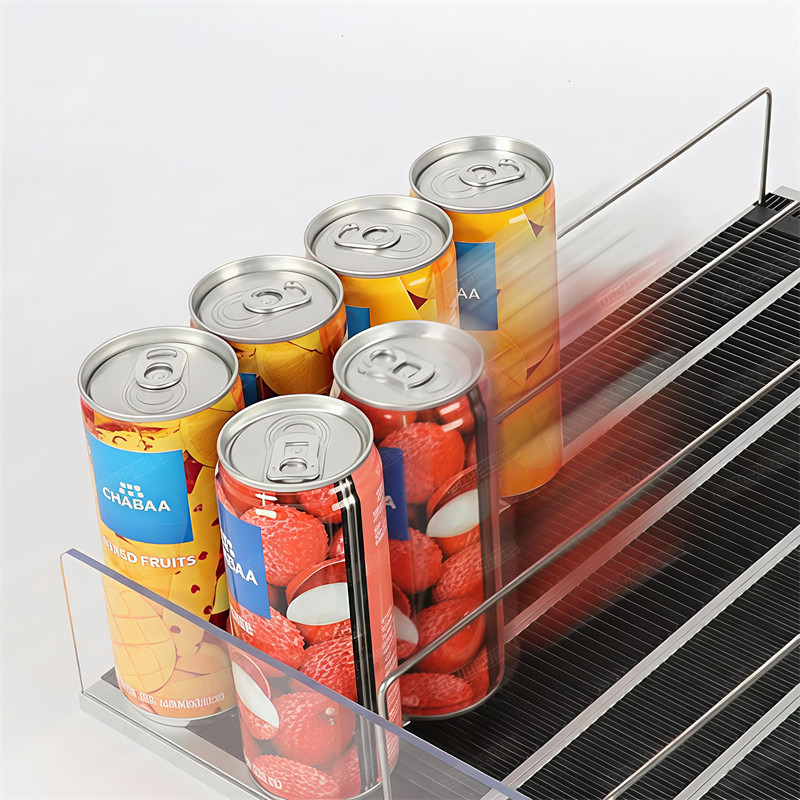 Close-up of drink cans resting on a black ABS roller track between wire dividers, showing the rolling contact line