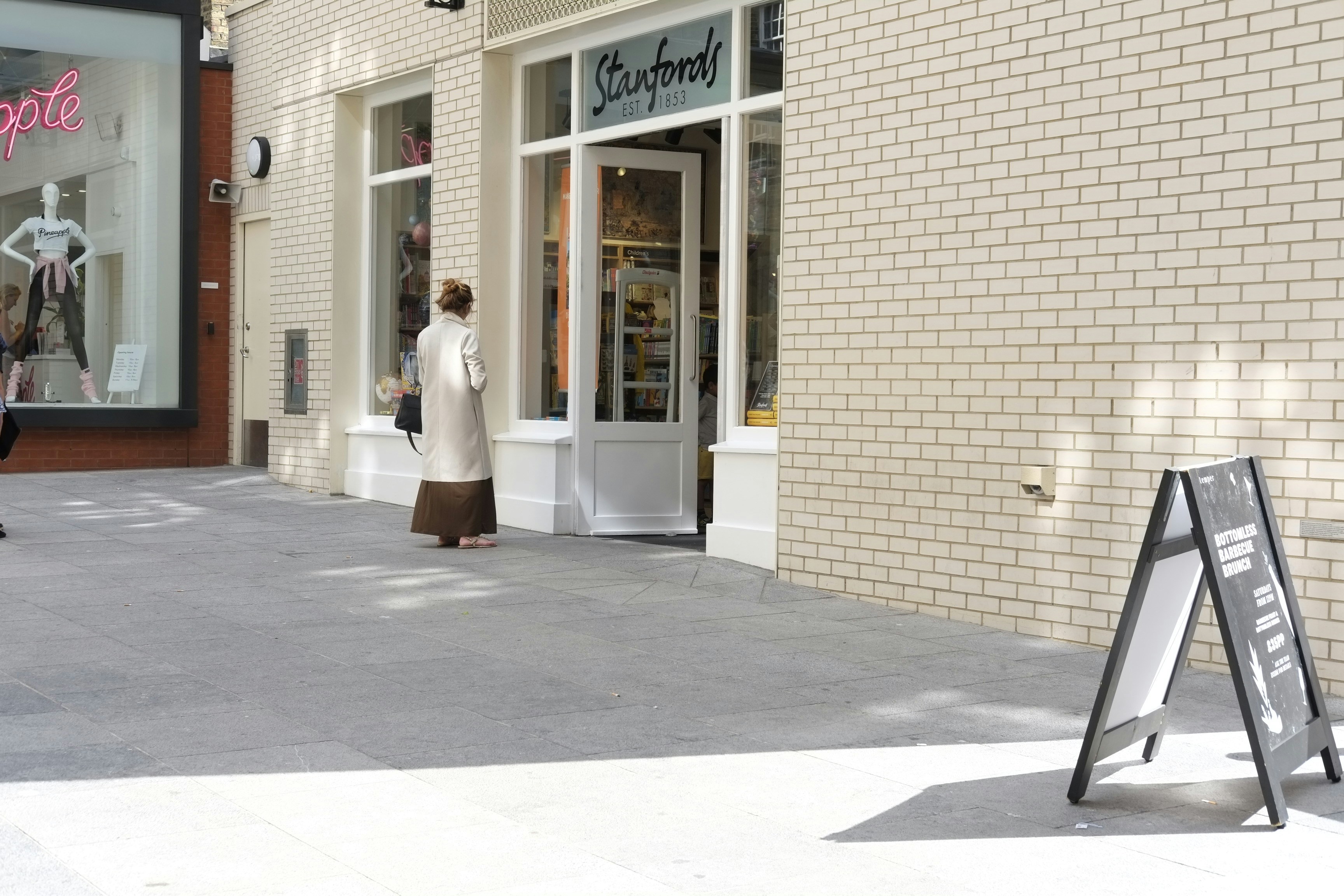 A modern metal A-frame sidewalk sign in front of a boutique store.