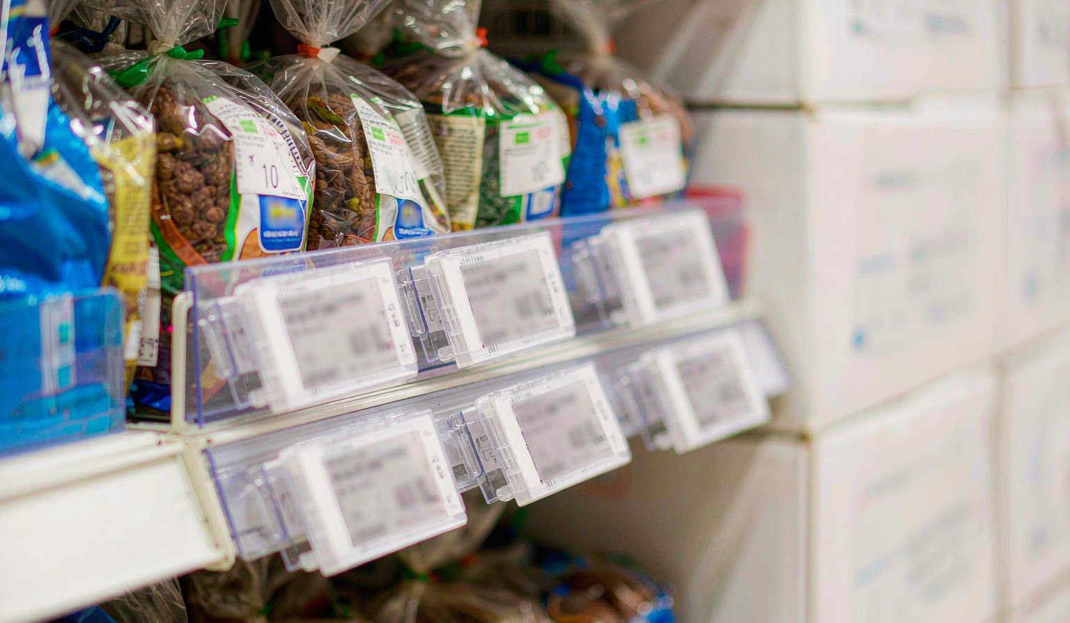Supermarket gondola shelves fitted with clear shelf-edge price tag holders holding white price cards