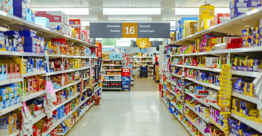 A well-stocked supermarket snack aisle where every product group sits in its own lane