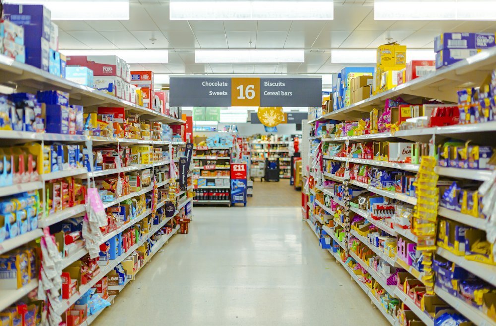 Supermarket grocery aisle with fully stocked shelves of biscuits, chocolate and sweets, with hanging strip merchandising
