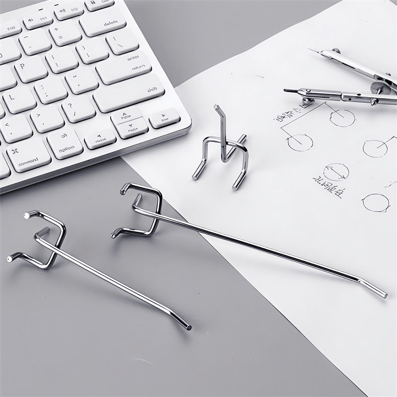 Chrome double-prong display hooks and a dimensioned drawing sheet laid out beside a computer keyboard