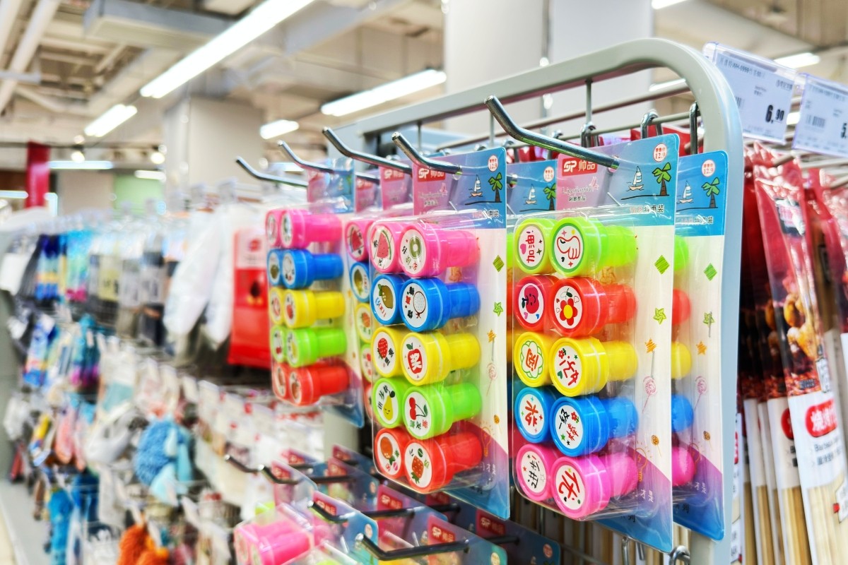 Colourful carded stationery and small gift packs hanging from silver wire hooks on a white coated wire display rack