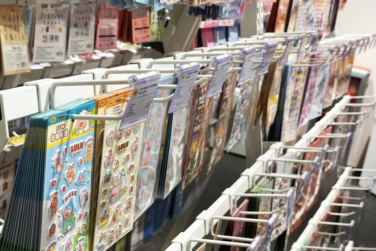 Close view of white powder-coated double-prong hooks holding sticker sheets and carded stationery in a densely spaced retail hook field